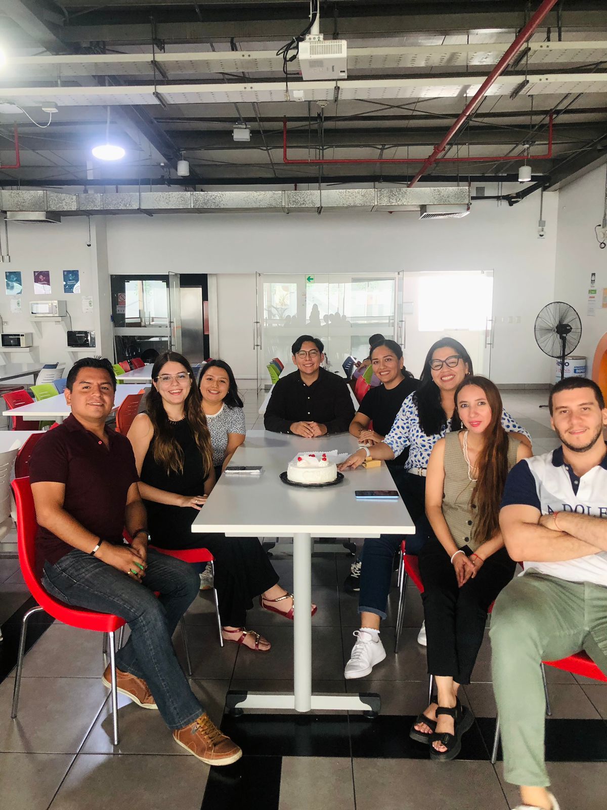 Equipo sentado alrededor de una mesa con un pastel